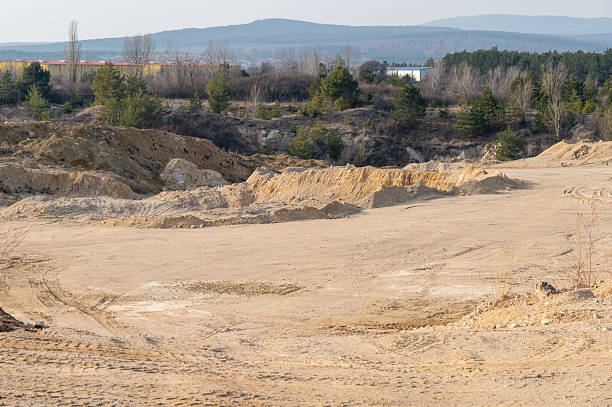 istock Quarry excavation site with exposed soil and forest backdrop 2216088103