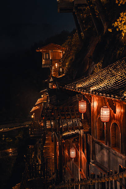 istock Scenic illuminated pathway winding through Wangxian Valley Town at night, blending natural rock formations and traditional Chinese architecture in a peaceful mountain setting. 2216094339