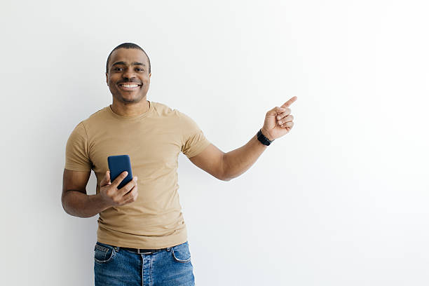 istock Smiling Black Man Holding Smartphone And Pointing Aside At Copy Space 2216094651