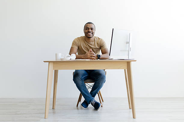 istock Black Man Sitting At Desk With Computer And Smiling At Camera 2216094791