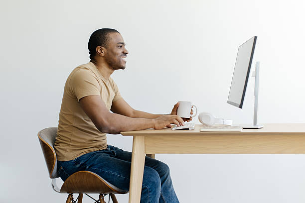 istock Smiling African American man working on desktop computer and drinking coffee 2216095123