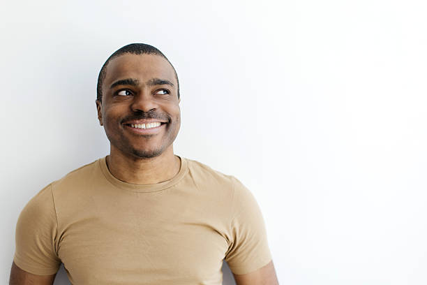 istock Smiling African American man in beige tshirt, looking upward with thoughtful expression 2216095684
