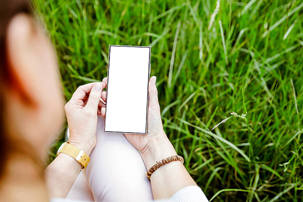 istock Smartphone with blank screen with space for text on natural green garden background with grass and natural leaves in daylight. 2216102646