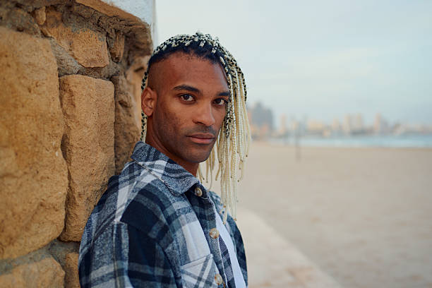 istock Young man with braided hair looking at camera on a beach 2216102859