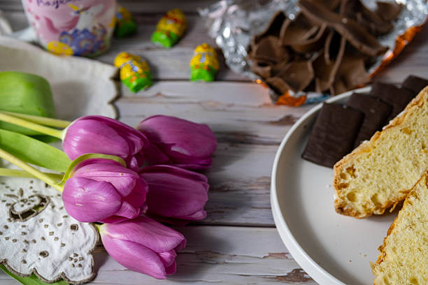 Symbols of Easter lunch in Italy. Chocolate and Easter dove: traditional Italian dessert made only for Easter. In the background a bunch of pink tulips, a typical spring flower