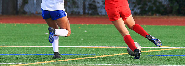High School Soccer player dribbling the ball down the field with the defender chasing during a game