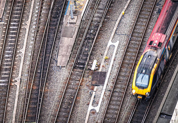 Motion blur on a single train leaving a station, next to multiple empty tracks.