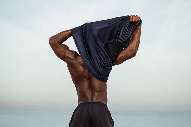 istock Athletic Man Removing Shirt Outdoors During a Workout by the Sea 2216110946