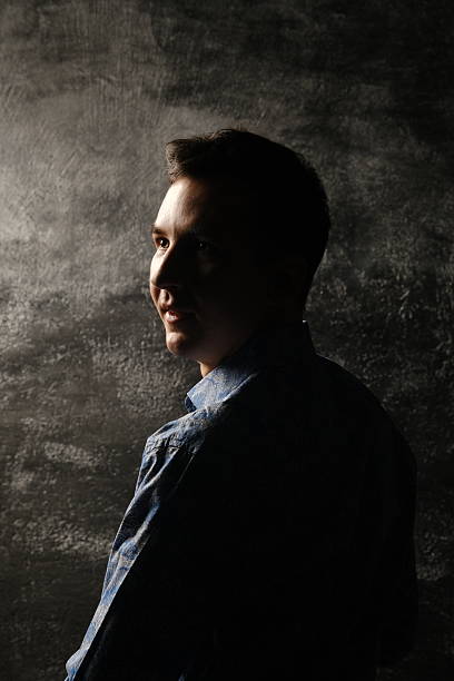 A captivating and intriguing profile silhouette illuminated in moody light, set against a richly textured background
