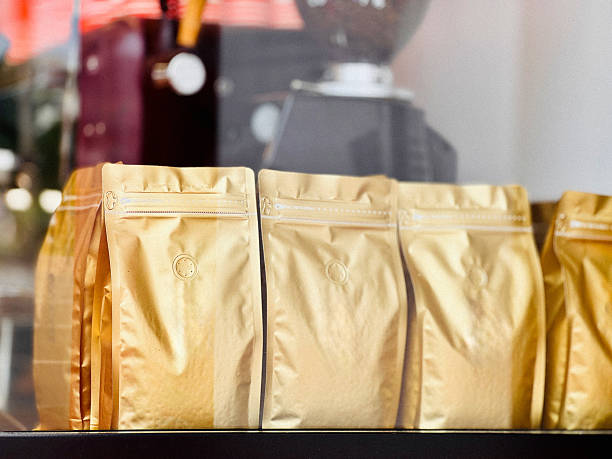 On top of three stacked coffee sacks, there is a chick-yellow coffee cup placed on a matching chick-yellow saucer.