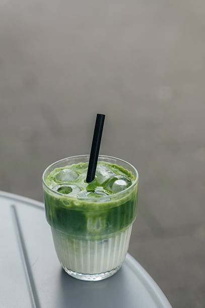 Refreshing iced matcha latte with a black straw, served on a table in an outdoor setting
