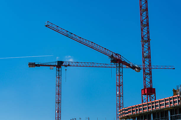 istock Construction cranes towering against clear blue sky at building site 2216116738