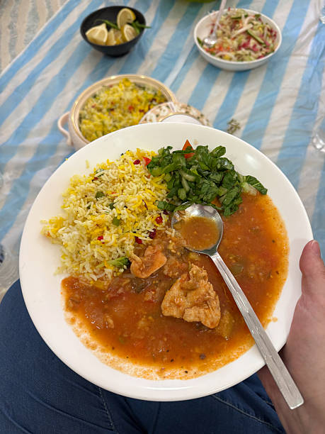 Traditional Omani Biriyani Rice dish with cooked chicken and vegetable stew served sitting home on the floor