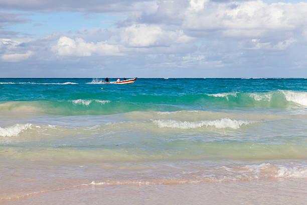 Idyllic view showcasing gentle ocean waves lapping on the shore under a cloudy sky, with a boat on the water adding charm to the peaceful environment