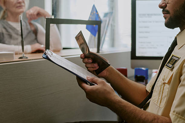 A border officer reviews a traveler’s passport and documents at an inspection counter.