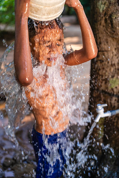 Sri Lankan young boy bathing outside his parents house, Sigiriya, Sri Lanka (Ceylon)