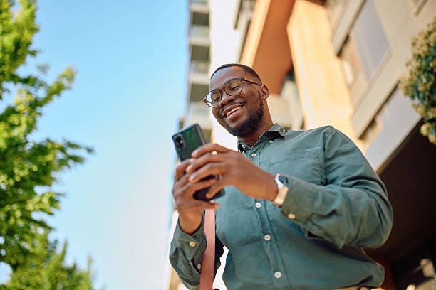 istock Smiling businessman using smartphone in front of modern building 2216125468