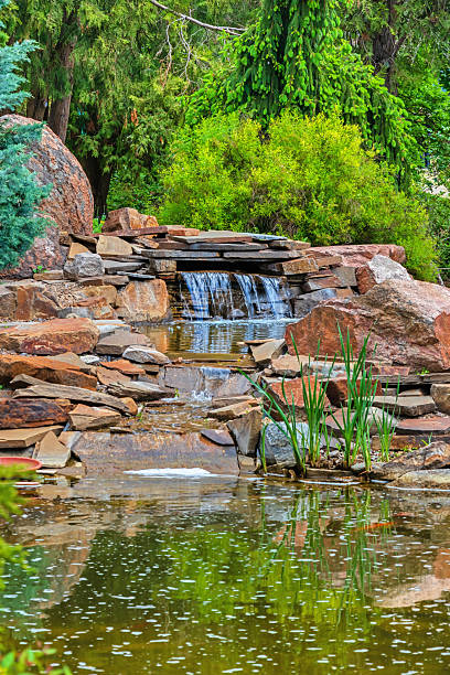 istock Small waterfall and stream near decorative pond. Garden design with stones 2216127138