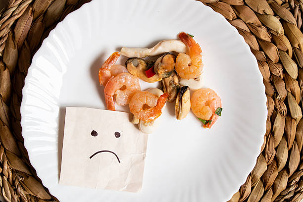 Seafood shrimp and squid are lying on a plate and a sad smiley face is drawn next to it