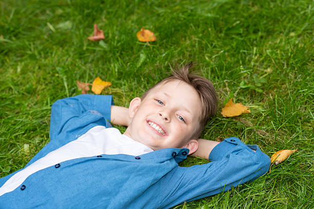 istock happy boy lying on green grass 2216127827