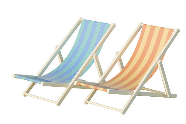 Stack of brightly coloured sun loungers ready for hire on the beach on a sunny summers day. Holiday makers hire the seats for the day to allow them to sun bath and get a sun tan whilst relaxing on vacation.