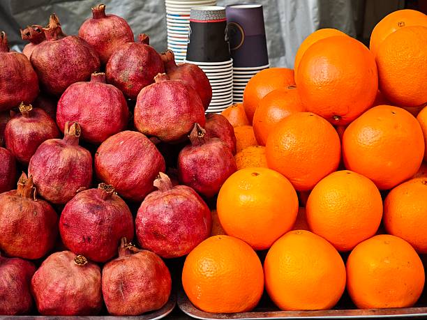 Fresh pomegranates and oranges are piled high, creating a vibrant and colorful display at a market, ready to be enjoyed