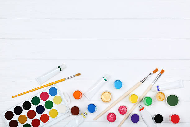 istock Colorful gouache paints and brushes on white wooden table 2216138517