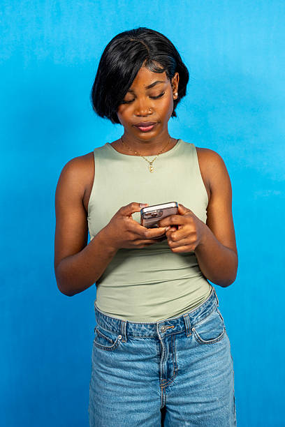istock Young woman using smartphone on blue background 2216138595