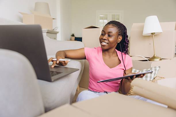 istock Young African American woman organizing her move using laptop and tablet 2216138679