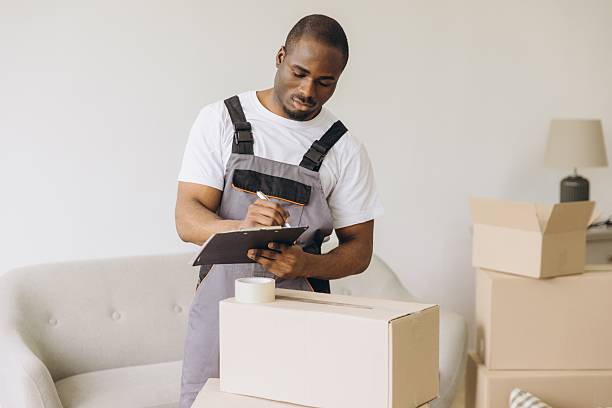 istock African American mover writing on clipboard checking boxes during house move 2216139329