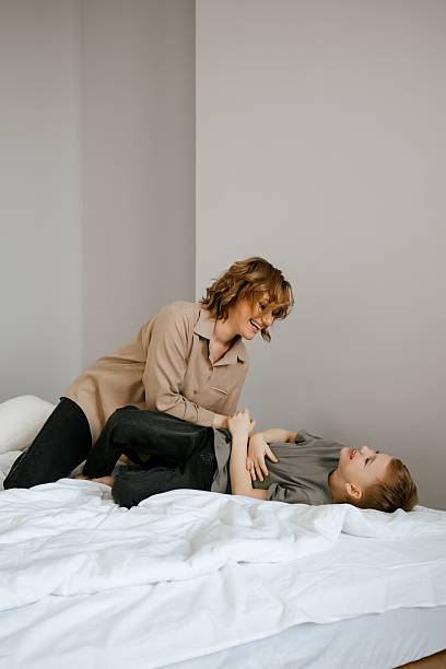 istock Playful Mother and Child Laughing on a Bed 2216147798