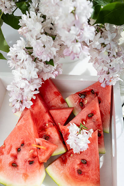 istock a cup with clouds on a blue background with tea and sliced watermelon slices. A strong hot drink for breakfast, a bouquet of lilacs in a vase 2216149513