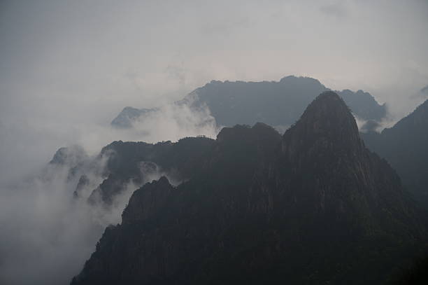 China,  Huangshan, The yellow mountains in fog, misty rain.Chinese man looking out at mountains