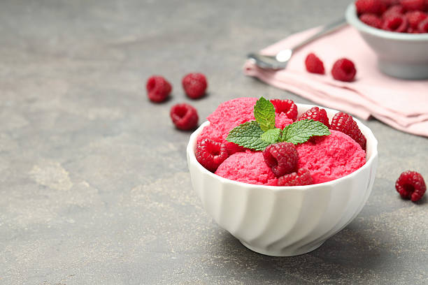 istock Delicious raspberry sorbet, fresh berries and mint in bowl on gray textured table, space for text 2216152636