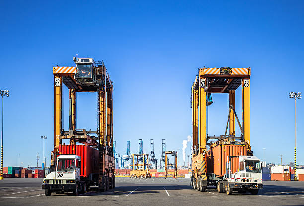 istock Two Straddle Carriers and Cargo Trucks at Container Terminal in Tacoma, Washington on a Sunny Day 2216153806