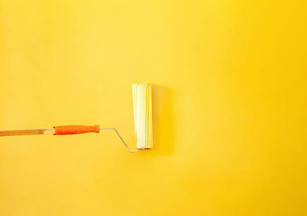 istock The roller paints the wall yellow 2216155026