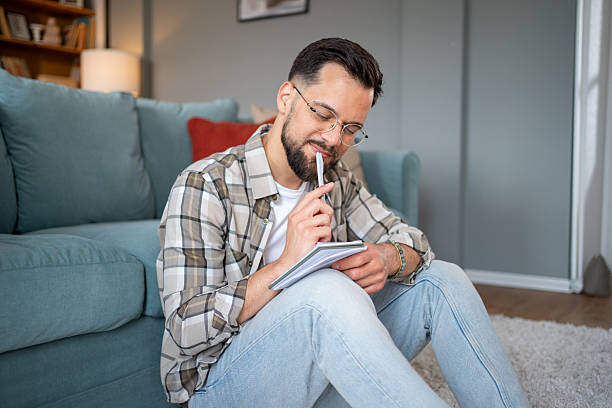 istock Young adult man writing in notebook at home 2216155606