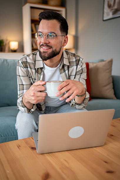 istock Young man working remotely from home enjoying a cup of coffee 2216155721