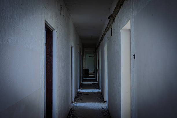 istock Dim abandoned hotel corridor strewn with debris and missing fixtures; doorframes recede into darkness, conveying urban decay, eerie atmosphere and the appeal of exploration photography. 2216156723
