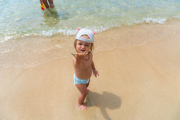 a little girl smeared with sand points to the camera