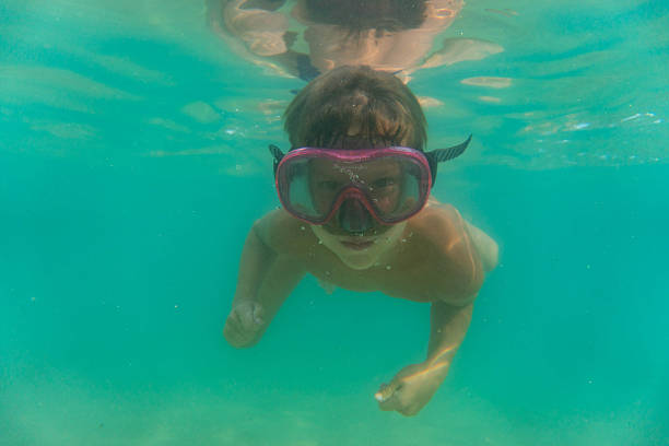 portrait of a boy diving in the water with a diving mask and looking at the camera