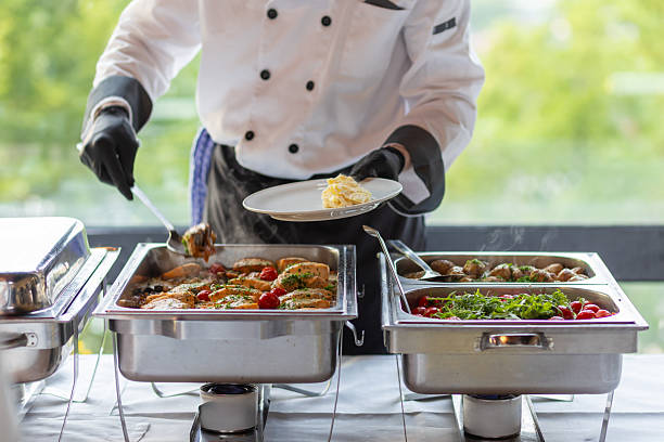 istock Chef serving a delicious buffet meal featuring grilled chicken, fresh vegetables, and flavorful sides at a catering event 2216157750