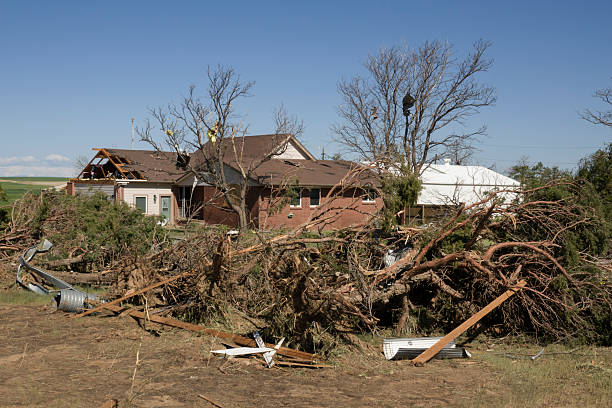 Parts of a roof and walls are ripped off a farm home as insulation remains stuck in trees and household items are scatted for miles after an EF2 tornado struck on May 18, 2025 in west Bennett, Colorado. Two days after the storm, trees sit sideways, uprooted. Corrugated metal from multiple grain elevators are wrapped around poles and the nearby solar farm.