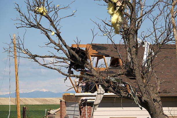 Parts of a roof and walls are ripped off a farm home as insulation remains stuck in trees and household items are scatted for miles after an EF2 tornado struck on May 18, 2025 in west Bennett, Colorado. Two days after the storm, trees sit sideways, uprooted. Corrugated metal from multiple grain elevators are wrapped around poles and the nearby solar farm.