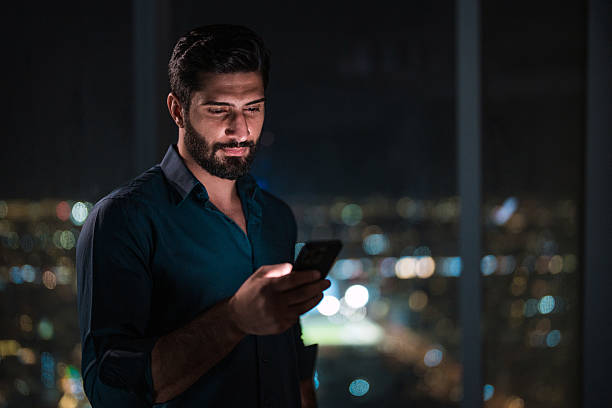 istock Focused Young Arabic Male Using Smartphone in Modern Home Overlooking Riyadh 2216163437