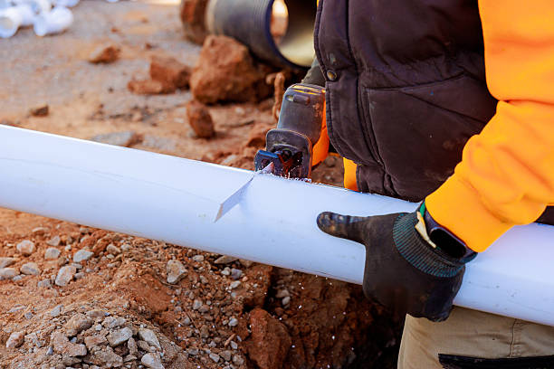 istock Worker cuts through white pipe with saw at construction site during works day 2216176239