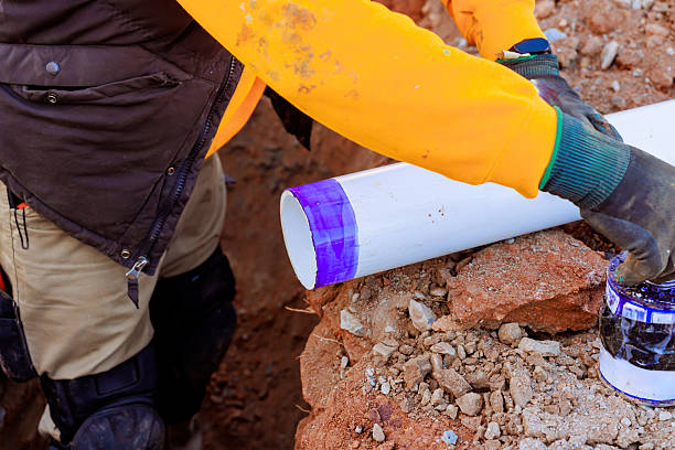 istock Construction worker applying adhesive to PVC pipe for plumbing project in residential area 2216176247