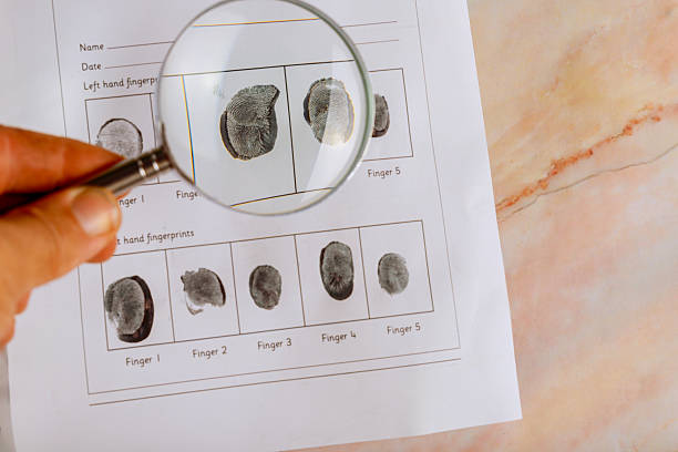istock Examination of left hand fingerprints using magnifying glass for analysis documentation at an unidentified location 2216176463