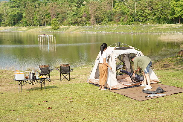 istock Couple Setting Up a Tent by the Lakeside 2216182045