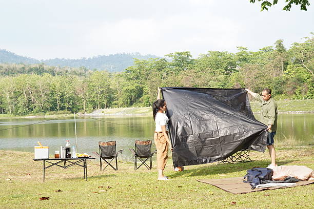 istock Couple Setting Up a Tent by the Lakeside 2216182110